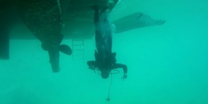 Yolda yürür gibi teknelerin altında baş aşağı yürüyor